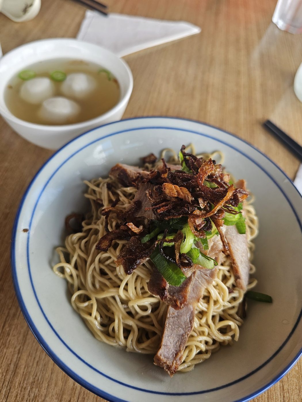 A bowl of loo mee noodles in broth with shredded chicken and spring onion